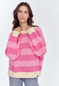 Różowo-kremowy sweter dziany w paski z przerośniętymi rękawami i żebrowanym wykończeniem. Miękka faktura, luźny krój i wyraźny kontrast kolorów w paskach.