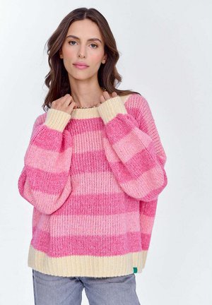 Różowo-kremowy sweter dziany w paski z przerośniętymi rękawami i żebrowanym wykończeniem. Miękka faktura, luźny krój i wyraźny kontrast kolorów w paskach.