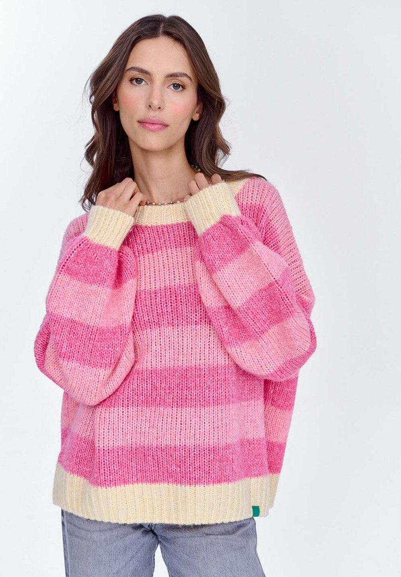 Różowo-kremowy sweter dziany w paski z przerośniętymi rękawami i żebrowanym wykończeniem. Miękka faktura, luźny krój i wyraźny kontrast kolorów w paskach.