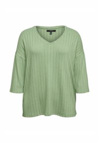 Haut vert clair à col en V avec manches 3/4, présentant une texture côtelée verticale et une coupe décontractée. Confectionné dans un tissu doux et respirant.