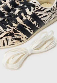 Tenisky s leopardím vzorem, černými koženými pruhy, strukturovaným svrškem a bílými tkaničkami na boku. Klasický střih; gumová podrážka.