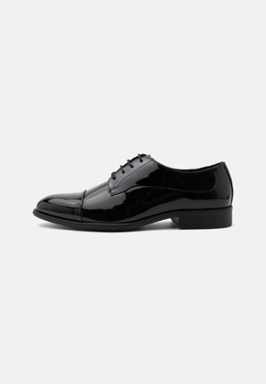 Scarpa oxford formale in pelle verniciata nera con lacci e tacco basso, vista laterale su sfondo bianco.