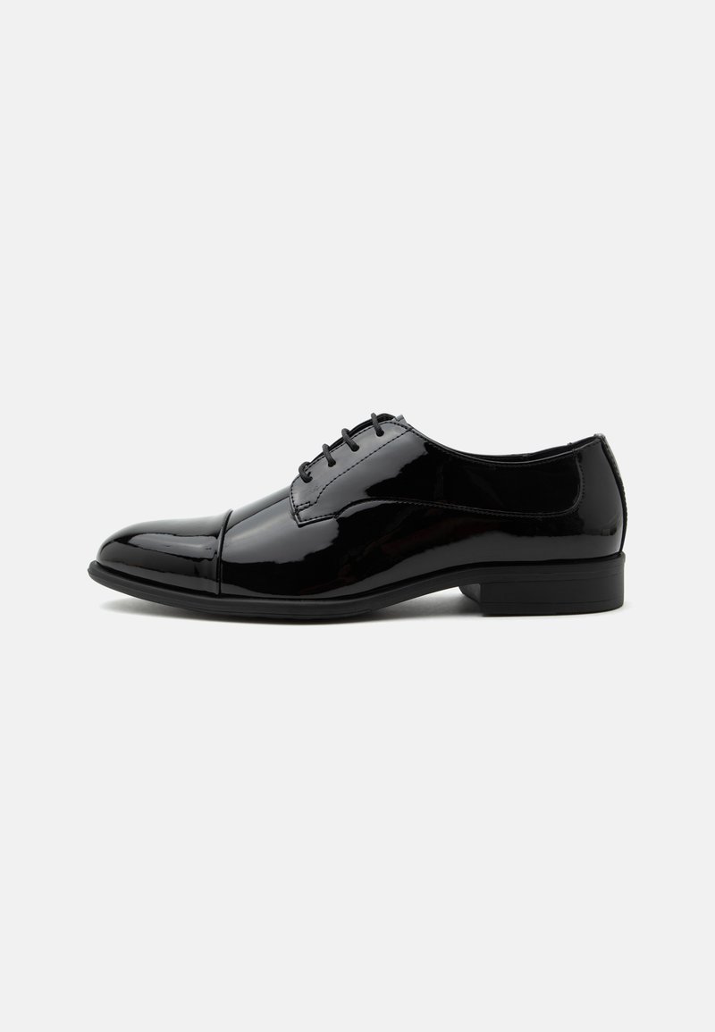 Chaussure oxford formelle en cuir verni noir avec lacets et petit talon, vue de côté sur fond blanc.