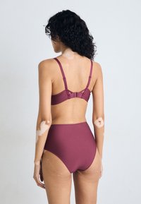 Burgundy színű bikini szett, magas derekú alsó résszel és állítható pántos melltartóval, letisztult textúrával és minimalista dizájnnal.