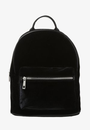 Sac à dos en velours noir avec un dessus arrondi, une poche avant zippée argentée et une petite poignée de transport en haut.