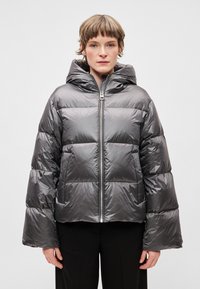 Fényes sötétszürke színű, bélelt téli kabát. Kapucnival, elöl cipzárral és harang alakú ujjakkal rendelkezik. Simább tapintású, steppelt részekkel.