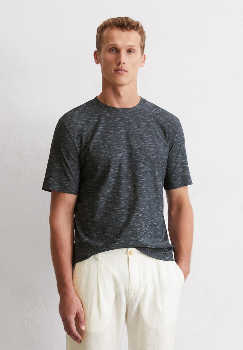 Graues T-Shirt mit kurzen Ärmeln und strukturiertem, melierten Muster. Rundhalsausschnitt, lässiger Schnitt, kombiniert mit hellen Hosen.