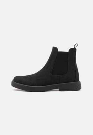 Stivali Chelsea neri in suede con pannelli laterali elasticizzati e linguetta. Presentano una finitura testurizzata e una suola piatta in gomma resistente.