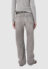 Jasnoszare dżinsy o luźnym kroju i prostych nogawkach, z tylnymi kieszeniami z detalami w postaci przeszyć oraz zdobionym czarnym paskiem.