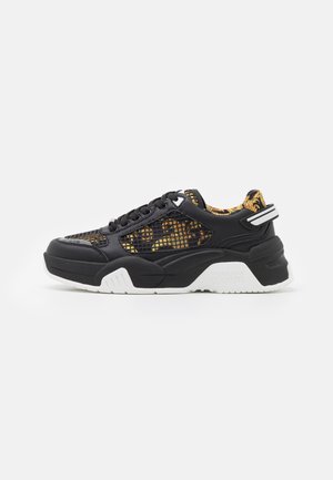 Zwart-gouden sneakers met patroon, dikke witte zool, veterluiting aan de voorkant en mesh-details langs de zijkanten en de neus van de schoen.