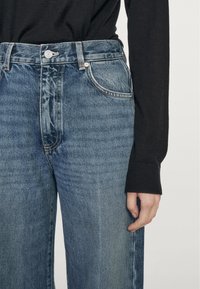 Dżinsy z wysokim stanem, tapered fit, w jasnoniebieskim kolorze z subtelnym wyblaknięciem, z klasycznymi kieszeniami i detalami przeszyć.