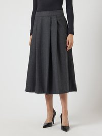 Falda midi de lana gris con pliegues frontales, cinturilla ajustada y silueta acampanada. Se lleva con tacones negros de punta.