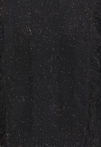 Tissu noir tricoté avec des motifs en torsades et de petites taches blanches, présentant des détails à franges le long des bords.