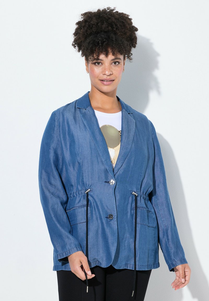 Lätt denimblazer i blått, med avslappnad passform, dragsko i midjan och två framfickor. Knappstängning och långa ärmar.