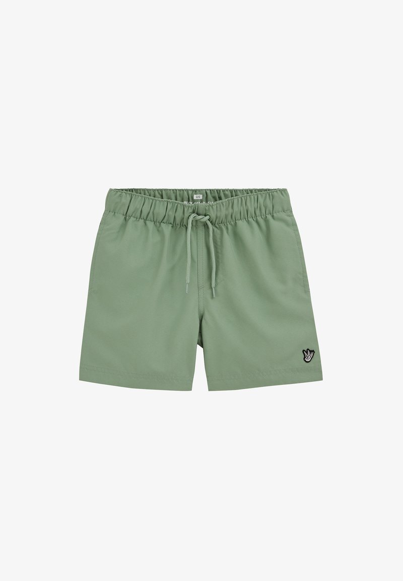 Shorts décontractés vert clair avec taille élastique et cordon de serrage, ornés d'un petit patch noir et blanc en forme de main sur la jambe gauche.