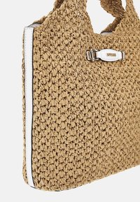 Sac à main en paille tressée de couleur marron clair, avec une surface texturée, des accents blancs et un emblème de logo avec du matériel en argent.