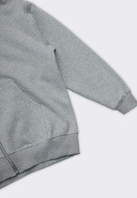 Felpa grigia con zip realizzata in tessuto morbido e texturizzato. Presenta maniche lunghe, una tasca frontale e polsini e orlo a costine.