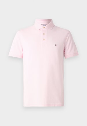 Pink polo shirt featuring a three-button placket, short sleeves, and a small logo on the left chest. Made from a smooth cotton fabric.