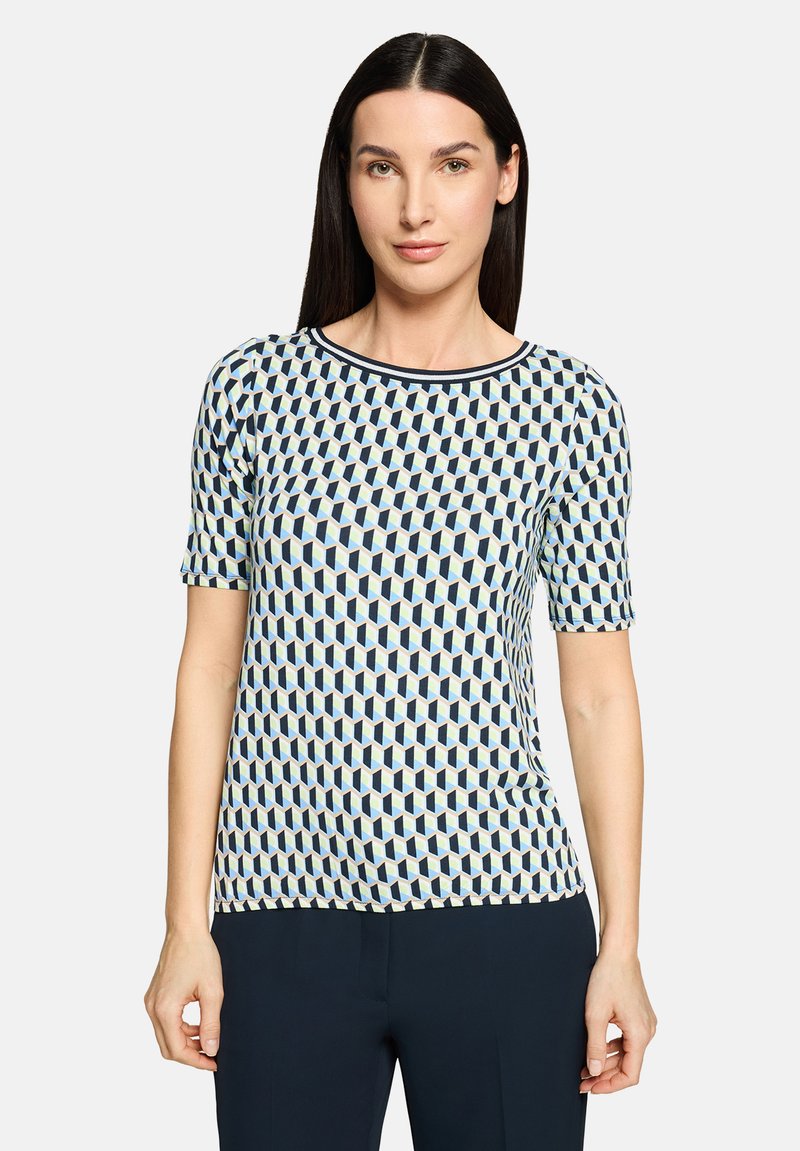 Haut à manches courtes avec un motif géométrique bleu, blanc et vert clair. Il présente un col rond et une texture tricotée.