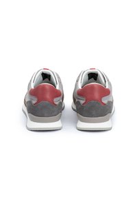 Sneaker in suede grigio con dettagli in pelle rossa, lacci bianchi e suola imbottita. Presentano un design elegante con punta arrotondata e pannelli testurizzati.