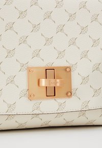 Borsa in pelle bianca con un motivo a conchiglia a rilievo ripetuto, una chiusura in oro rosa con il nome del marchio "JOOP!" e rifiniture in metallo.