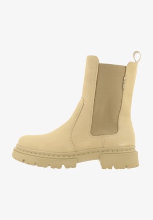 Beige ankle boot made from smooth fabric with a stretchy side panel, thick rubber sole, and a pull tab for easy wear.