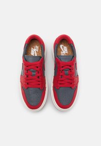 Paire de baskets Nike Air rouges et gris foncé avec semelles blanches et lacets rouges, vue de dessus sur un fond clair.