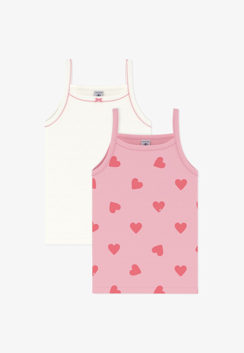 Δύο μπλουζάκια χωρίς μανίκια: ένα απλό λευκό με αντίθετες κόκκινες ραφές, το άλλο ροζ με διασκορπισμένα κόκκινα μοτίβα καρδιών.