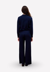 Navyblauwe gebreide trui en wijde broek set, met een relaxte pasvorm, ribbelmanchetten en een subtiele textuur.