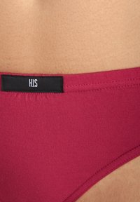 Burgunderfarbene Bikini-Hose aus glattem Stoff mit einem schwarzen Etikett, auf dem "H.I.S." steht, am Bund. Verfügt über einen niedrigen Schnitt und ein schlichtes Design.