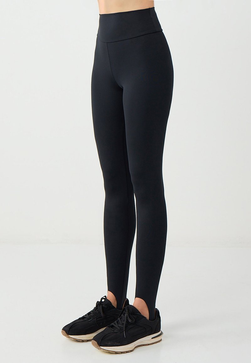 Leggings neri a vita alta realizzati in tessuto elasticizzato, dal design aderente, lungo fino alla caviglia, con una texture morbida e senza motivi visibili.
