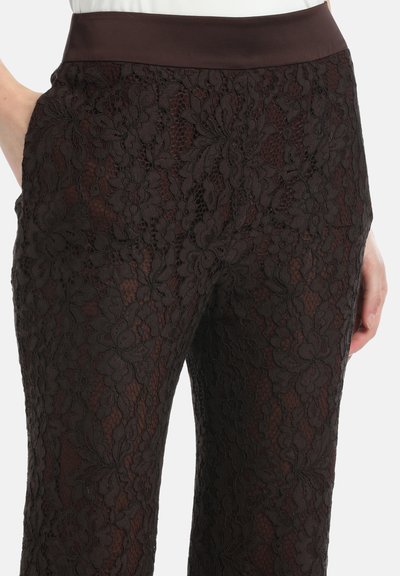 Kanten broek in donkerbruin met bloemenpatroon, semi-doorzichtig materiaal en een stevige tailleband. Voorzien van twee zijzakken voor gebruiksgemak.