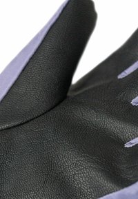 Musta teksturoitu hansikas matalla pinnalla, jossa on violetti yksityiskohta rannetta pitkin ja sileä sisävuori.