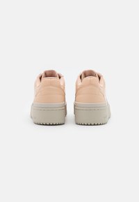 Tyylikkäät matalat tennarit pehmeässä vaaleanpunaisessa nahassa, jossa on sileä pinta. Kenkäparissa on paksu vaaleanharmaa kumipohja ja ommeltuja yksityiskohtia.