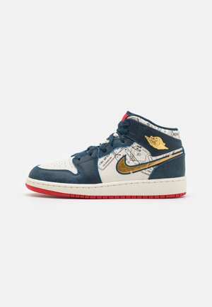 Vue de profil d’une basket montante avec des empiècements bleu marine, des panneaux blancs imprimés d’une carte, un logo doré en forme de swoosh et d’ailes, et une semelle extérieure rouge.
