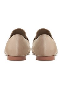 Beige suède instap schoenen met afgeronde achterkant en een soepele bruine zool. De textuur is zacht, met eenvoudige stiksels langs de naden.