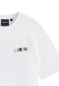 Hvid bomulds t-shirt med et multicolor "LEGACY" grafisk design på forsiden. Rund halsudskæring og korte ærmer. Blød tekstur.