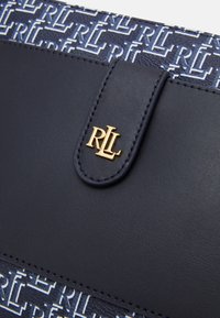 Navy blue handbag with a printed pattern and gold hardware. Features a textured surface and a magnetic flap closure with an embossed logo.