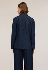 Czarna dżinsowa kurtka o wyraźnej sylwetce i długich rękawach, z kołnierzem w kształcie notcha i gładkim, teksturowanym wykończeniem.