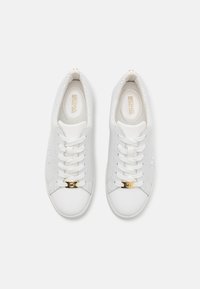 Hvite perforerte sneakers med en glatt tåhette, gull MK-emblem på snøringen og flate hvite snørebånd. Innvendig har de en merket innersåle.