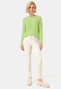 Light green knitted sweater with ribbed texture, paired with white drawstring pants and beige clogs. Simple design and relaxed fit.