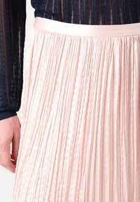 Faltet skjørt i myk rosa stoff med en blank overflate, med en jevn, bred midje og et strukturert design.