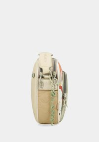 Bolso de hombro beige con estampado floral, acentos de cuero texturizado, cremalleras dobles y un charm verde colgando de un lado.