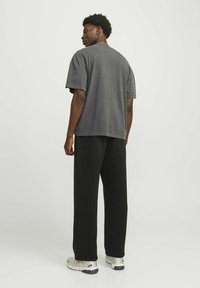Grå oversized t-shirt med korte ærmer, parret med sorte løstsiddende bukser. Outfittet har en afslappet silhuet og blød stoftekstur.