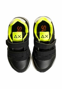 Sneaker nere con cinturini in velcro, interna gialla vivace e suola in gomma bianca a contrasto; presenta un logo sulla linguetta.