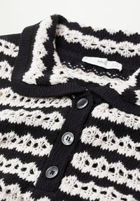 Cardigan tricoté en noir et blanc avec un motif en zigzag texturé, trois boutons noirs et un col rabattable.