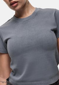 T-shirt grigio a maniche corte realizzato in un tessuto morbido e leggermente elastico. Presenta un collo a giro e cuciture pulite e minimal lungo i bordi.