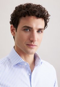 Lichtblauw en wit gestreept overhemdd met een spreidkraag, met een gladde textuur en knoopsluiting, gedragen door een mannelijke model.