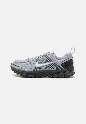 Szaro-czarny but do biegania Nike z białym logo Swoosh, siateczkowa cholewka i teksturowana podeszwa, pokazany z boku na białym tle.