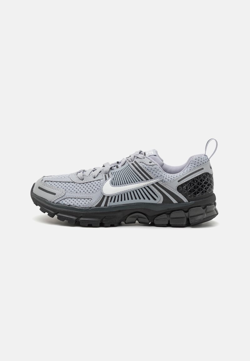 Chaussure de course Nike grise et noire avec logo swoosh blanc, empeigne en mesh et semelle texturée, vue de côté sur fond blanc.
